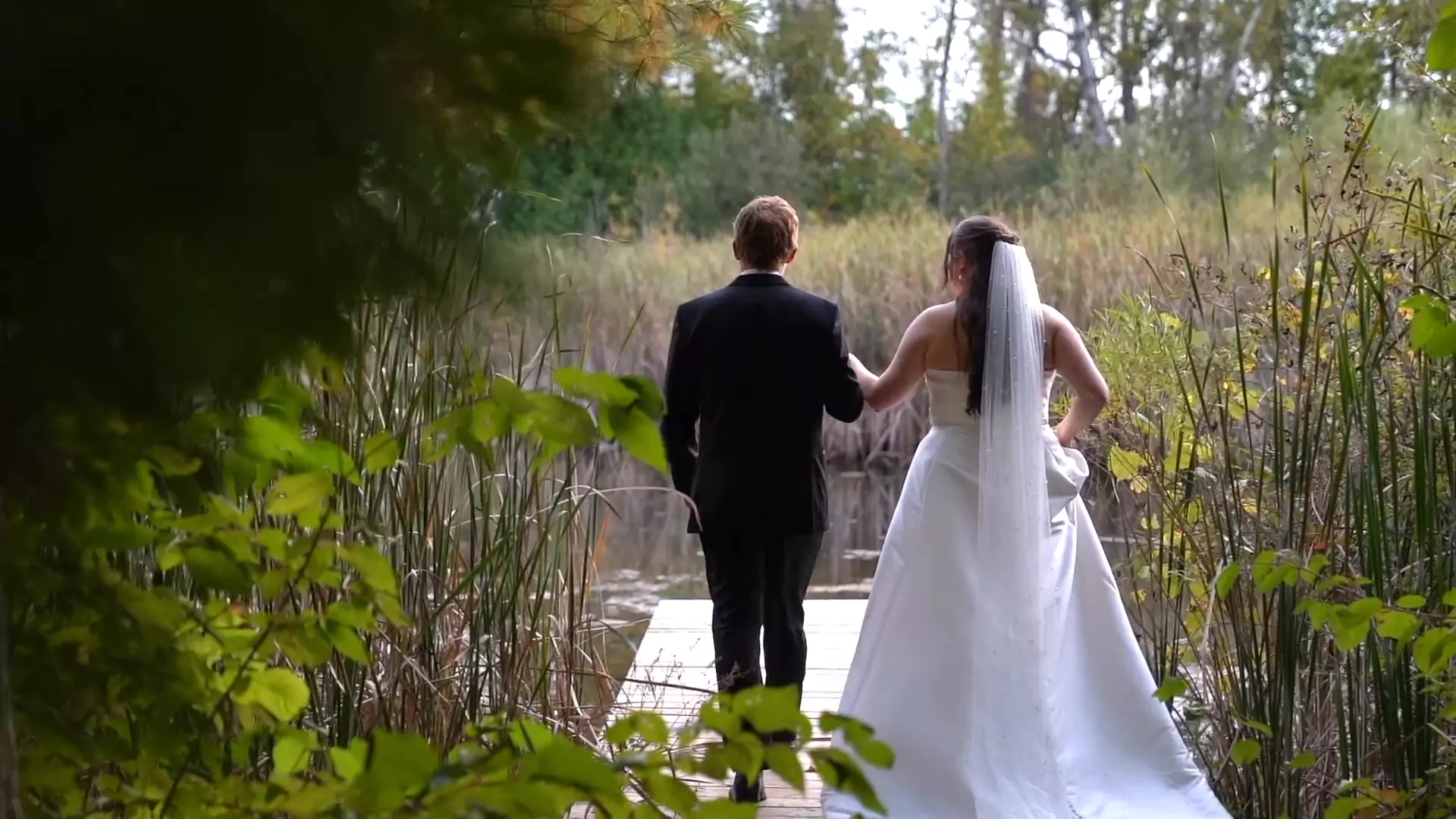 Olivia & Jacob facing away from the camera as they walk out for a romantic moment on the dock.